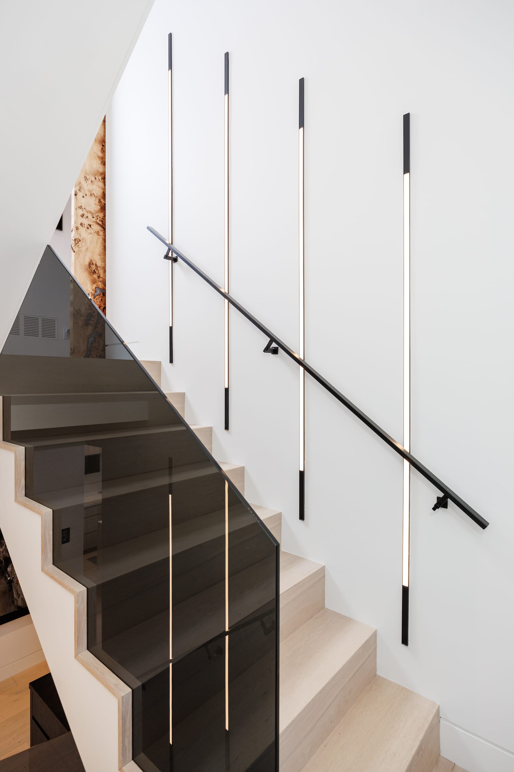Vertical linear wall lights follow the staircase at Ashton Manor